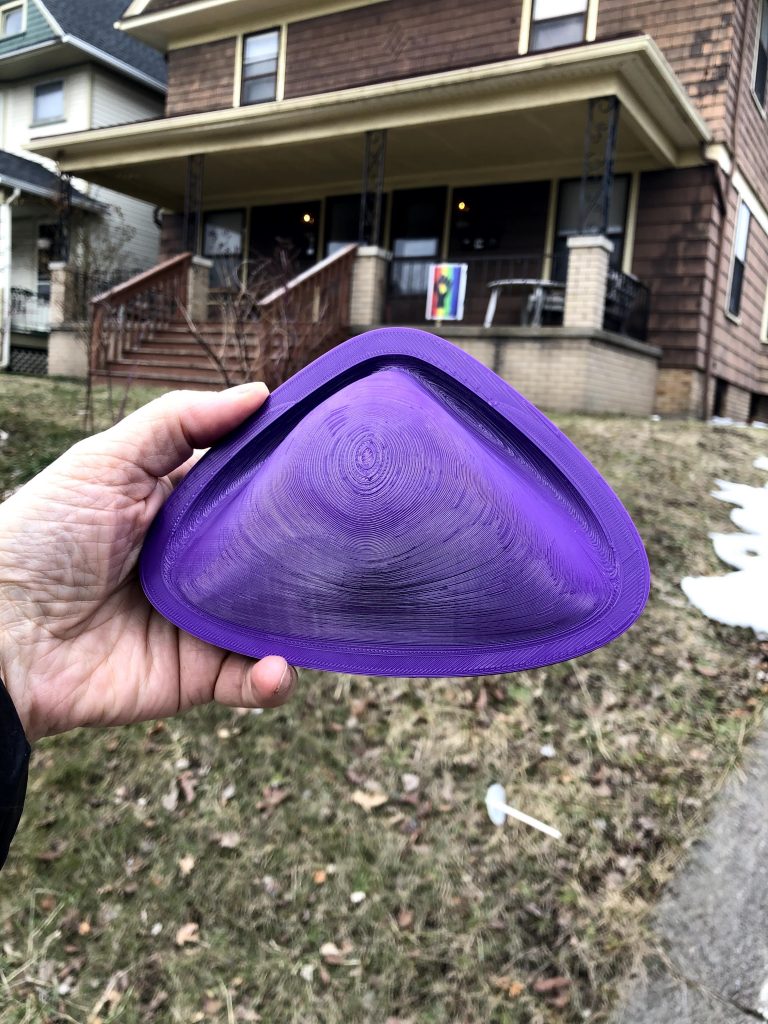 A 3D printed mask mold is held up outside
