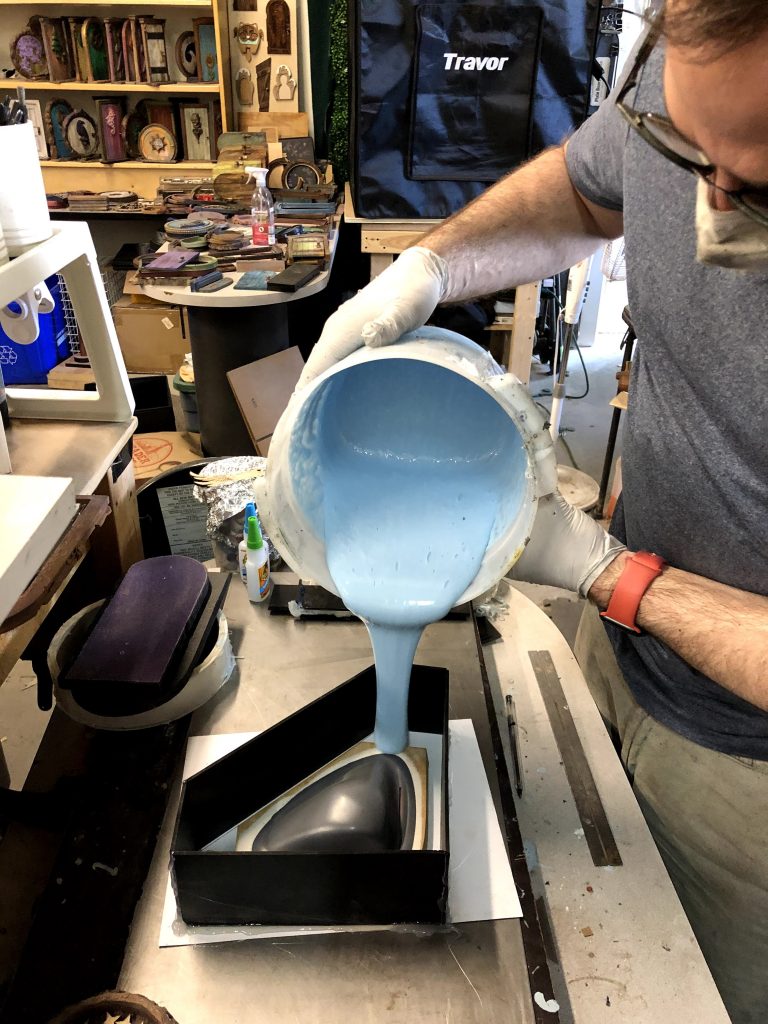 Man pours blue liquid into a mask mold for the vacuum formed mask